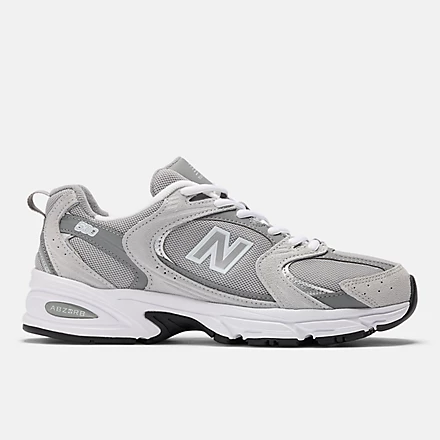 Grey and white shoe with a black rubber bottom. Large N for 'New Balance' between the rubber bottom and the laces.