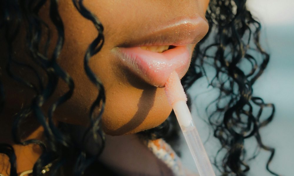 Image of girl applying lipgloss courtesy of Peter Kalonji on Unsplash